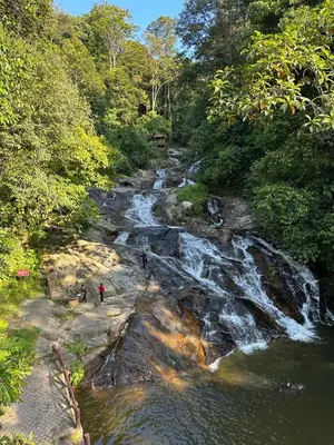people walking on the rocks near a river with a waterfall at D’Asam Homestay Baling in Baling