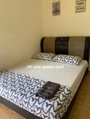 a bed with a black and white comforter on it at Chalet Naqib in Gerik