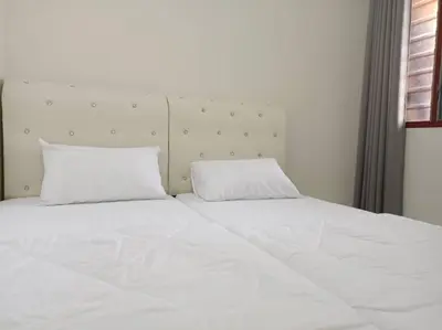 a white bed with two pillows on top of it at KhaAfi Homestay Seri Iskandar in Kampung Bota Kiri