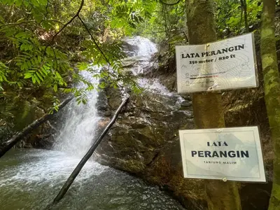 a waterfall with signs in front of a river at Sunny Lake House - Entire bungalow, 5 rooms, 16 persons in Behrang Hulu