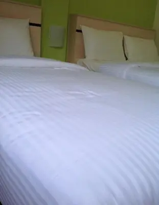 a large white bed with white sheets and pillows at Merlin Hotel George Town Penang in George Town