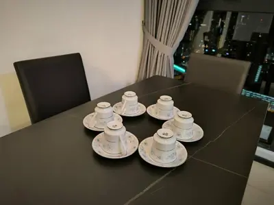 a table with four cups and saucers on it at Urban Suites, Best Seaview and Cityview in Town in Jelutong
