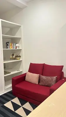 a red couch in a room with a book shelf at SohoMimi Seri Iskandar in Kampung Bota Kiri