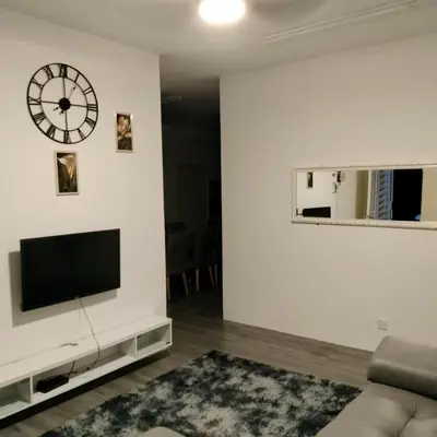 a living room with a tv and a clock on the wall at AZK HOMESTAY in Sungai Besar