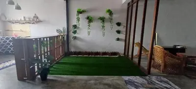 a living room with a green floor with plants at Cozy Nature Homestay - Free Wifi Disney Hotstar ADS in Nibung Tebal