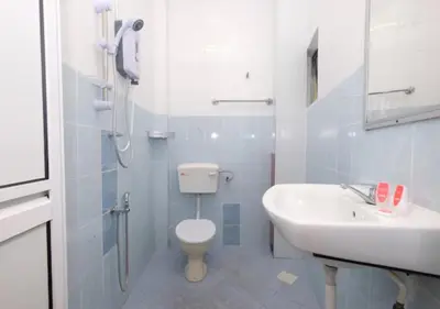 a white bathroom with a toilet and a sink at Hotel Tudor Home Inn Cameron Highlands in Brinchang