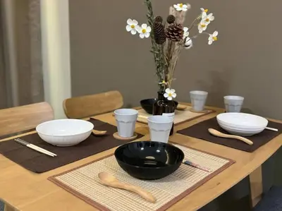 a wooden table with bowls and utensils on top at Urban Suites Stylish 3BR in Georgetown with Stunning Seaview in Jelutong