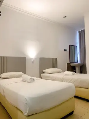 a hotel room with three beds and a flat screen tv at One Stop Hotel Ipoh in Ipoh