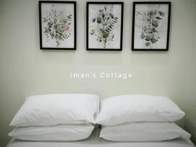 four framed pictures on a wall above a bed with four pillows at Iman Cottage Homestay Hospital Kulim Hitech in Kulim