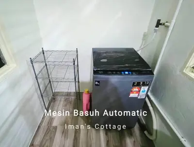 a washing machine sitting in a room next to a shelf at Iman Cottage Homestay Hospital Kulim Hitech in Kulim