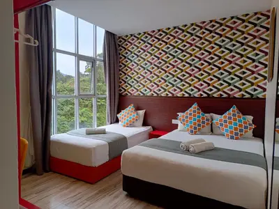 a bedroom with two beds and a wall of windows at Beautiful Marigold Hotel in Tanah Rata