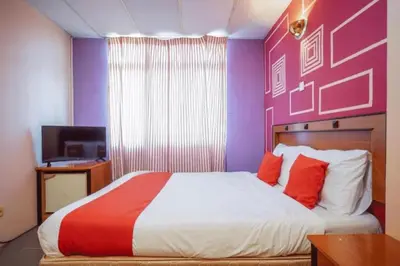 a bedroom with a large bed with a purple wall at DJ Seafront Hotel in Lumut