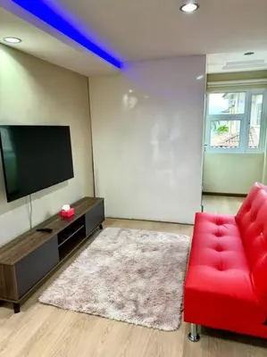 a living room with a red chair and a flat screen tv at YK Sweet home sungai petani 1 @ 16 people above in Sungai Petani