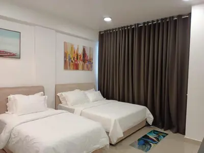 a bedroom with two beds and a window with curtains at RJ STUDIO 2- Kompleks Mutiara in Gua Musang
