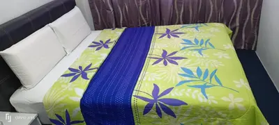 a bed with a blue and green blanket on it at Hotel Blue Orchid in Bayan Lepas