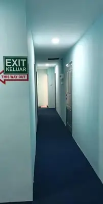 an empty hallway with a exit sign on the wall at Hotel Blue Orchid in Bayan Lepas