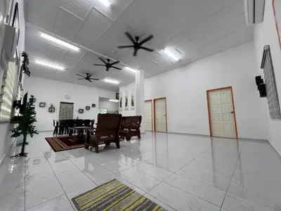 a living room with chairs and a table and ceiling fans at Agro Village Stay in Tapah