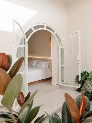a bedroom with a bed in a white room with plants at Mint Villa with Jacuzzi Pool in George Town