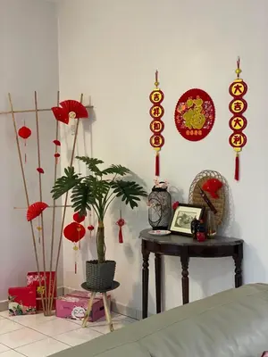 a room with a table with a plant and red decorations at Cozy Modern Classic Home in Ipoh in Ipoh