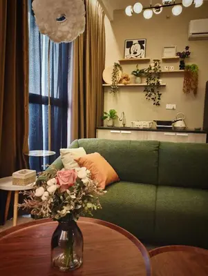 a living room with a green couch and a vase with flowers at Urban Suites 3 Rooms, Cat Theme & Romantic in Jelutong
