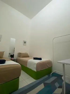 a small room with two beds and a table at Abu Fateh Homestay in Seri Iskandar