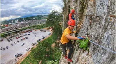 a man climbing a rock wall with a child on it at Putra 2 Homestay in Gua Musang