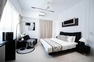 a white bedroom with a bed and a chair at Batu Ferringhi By The Sea Luxurious 2BR Suite 6 Pax in Batu Ferringhi