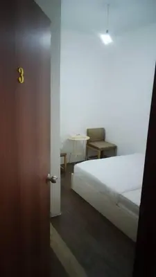 a bedroom with a bed and a table with a chair at GG 98 Hotel in George Town