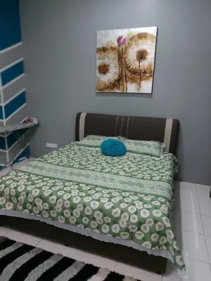 a bed with a green and white comforter on it at Puteri Homestay Sg Petani in Sungai Petani