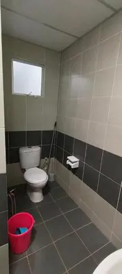 a bathroom with a toilet and a red bucket at ALEESYA Homestay at Emerald Avenue Brinchang in Brinchang