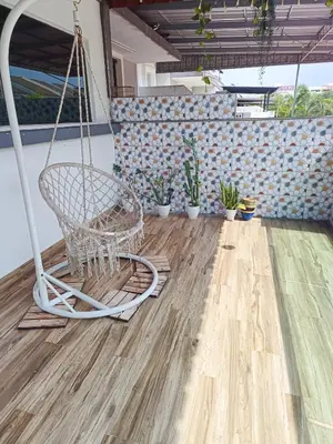 a swinging chair on a porch with potted plants at perdana homestay in Ipoh