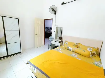 a bedroom with a yellow bed and a mirror at Manjung Point Homestay in Seri Manjung
