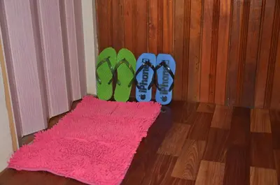 a pair of flip flops and a pink rug next to shoes at Country house Pulai Holiday Village in Gua Musang