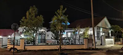 a white house with a fence and trees at night at Pantai Remis Homestay 118A in Pantai Remis