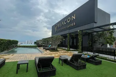 a building with chairs and a pool in the grass at Beacon Suites #Georgetown #RoofTopPool #23 #2Bedrooms in George Town