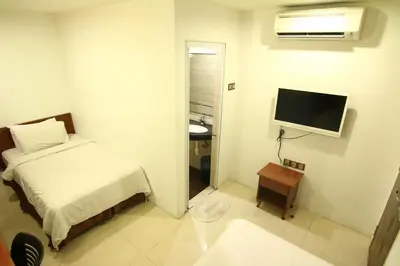 a small bedroom with a bed and a television at AG Hotel Penang in George Town