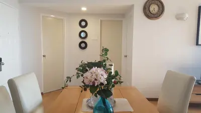a dining room with a table with a vase of flowers at Batu Ferringhi Seaview Apartment in Batu Ferringhi