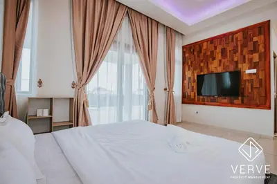 a bedroom with a white bed with a tv on the wall at Ipoh Garden Luxury House By Verve (14pax) in Ipoh