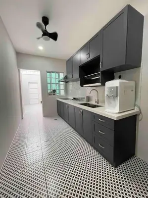 a kitchen with black cabinets and a white tiled floor at Modern Victorian Homestay in Jelutong