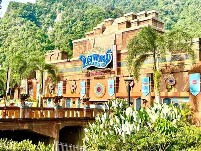 a building with palm trees in front of a mountain at Sunway Alpine Suites near Onsen and Themepark Tambun Ipoh by IWH in Ipoh