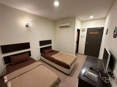 a bedroom with two beds and a desk with a computer at Ezzy In Hotel in Seri Manjung