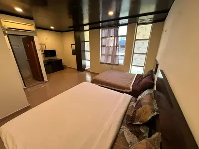 a room with a bed and a couch and windows at Ezzy In Hotel in Seri Manjung