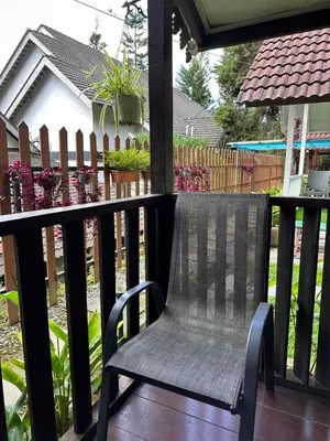 a black chair sitting on a porch with a fence at Hillside cottage tanah rata in Tanah Rata