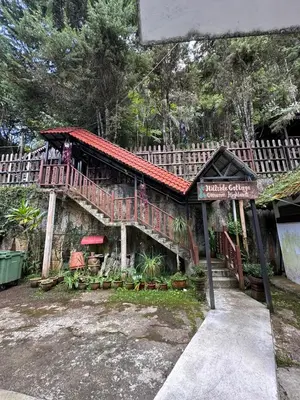 a house with a balcony and a sign in front of it at Hillside cottage chalet studio in Tanah Rata