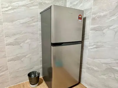 a stainless steel refrigerator in a room with a trash can at Emerald Avenue Brinchang Muji style in Brinchang