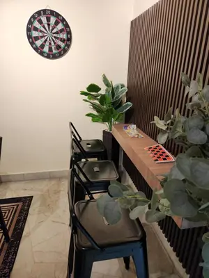 a dart board on a wall with two chairs and a table at Sun Shine Home by Ipoh Maju Stay in Ipoh