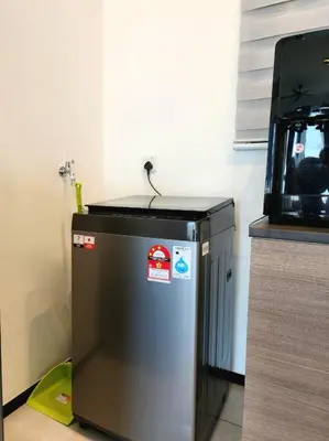 a small refrigerator in a kitchen next to a wall at Modern Luxe Island Suites #3BR in Jelutong