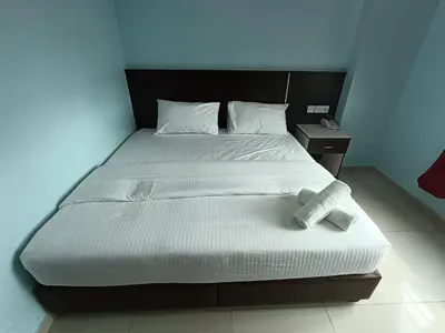 a bed in a room with a white bedspread at river hotel in Simpang