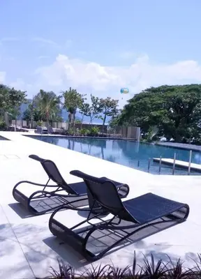 two lounge chairs sitting next to a swimming pool at By The Sea Deluxe Condo @ Batu Ferringhi Penang in Batu Ferringhi