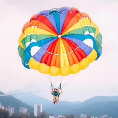 a person riding a colorful parachute in the sky at By The Sea Deluxe Condo @ Batu Ferringhi Penang in Batu Ferringhi